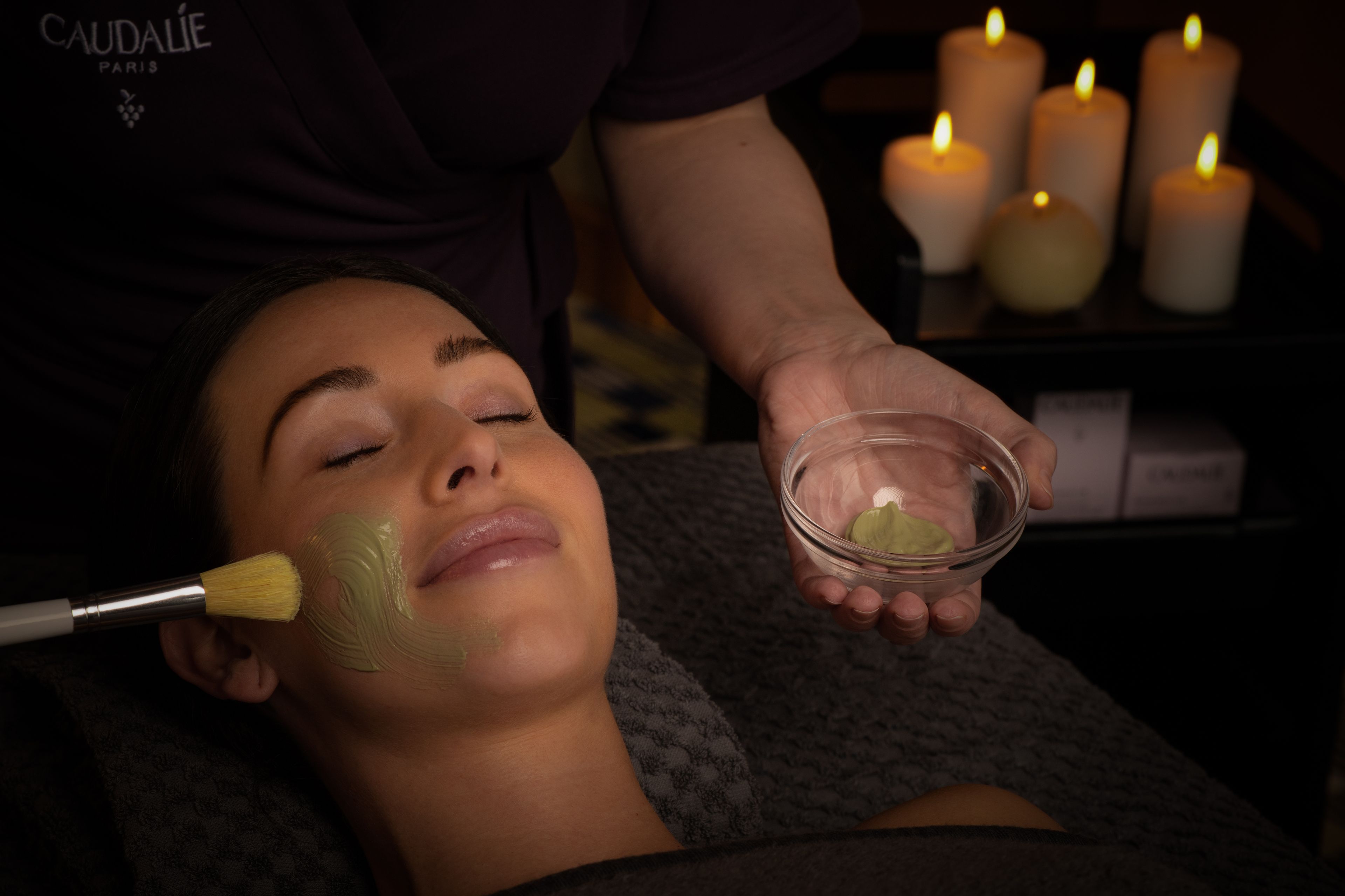 person receiving a facial mask from a spa technician