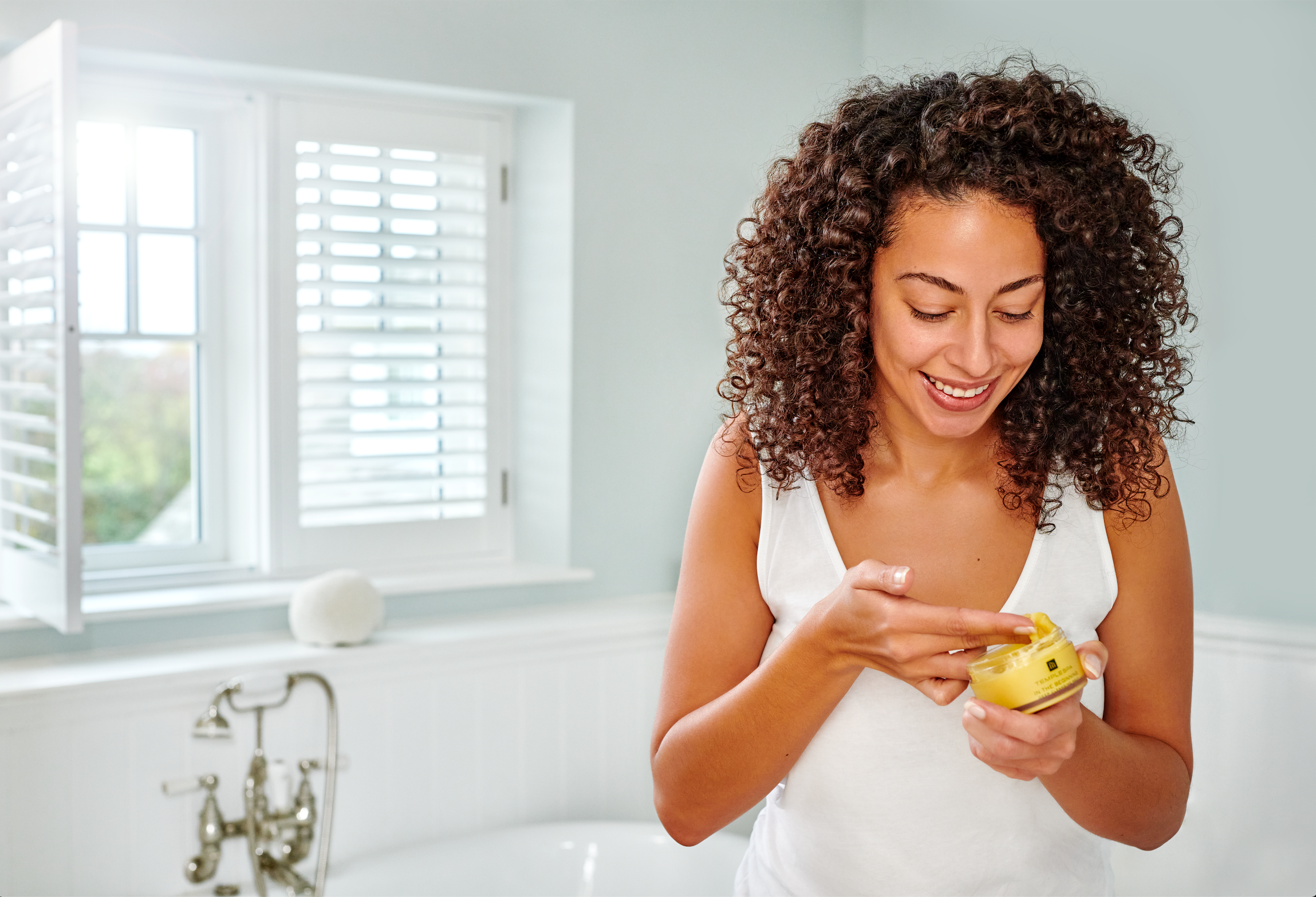 woman applying face cream in the bathroom