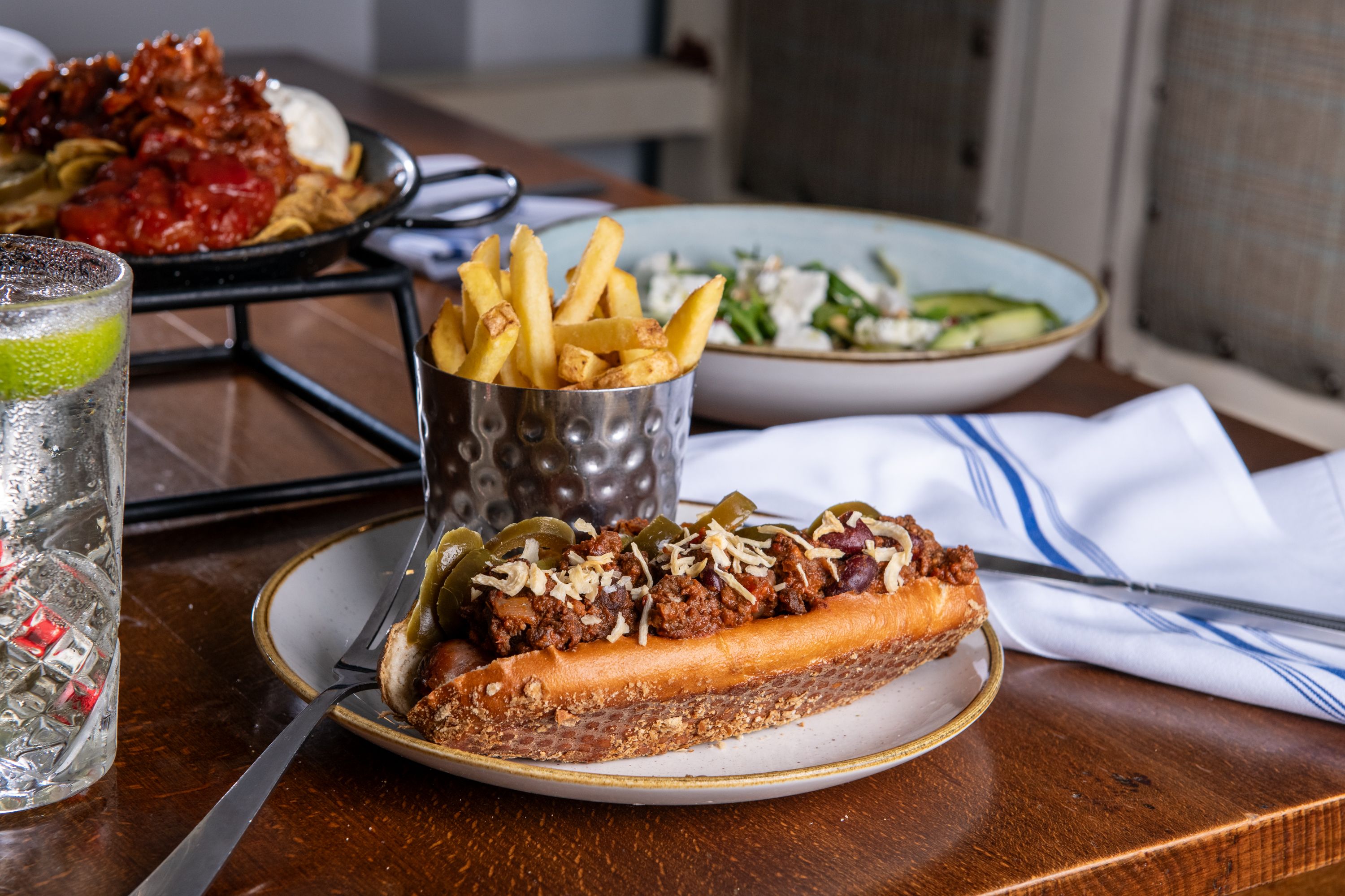 chili dog with chips and salad on a table