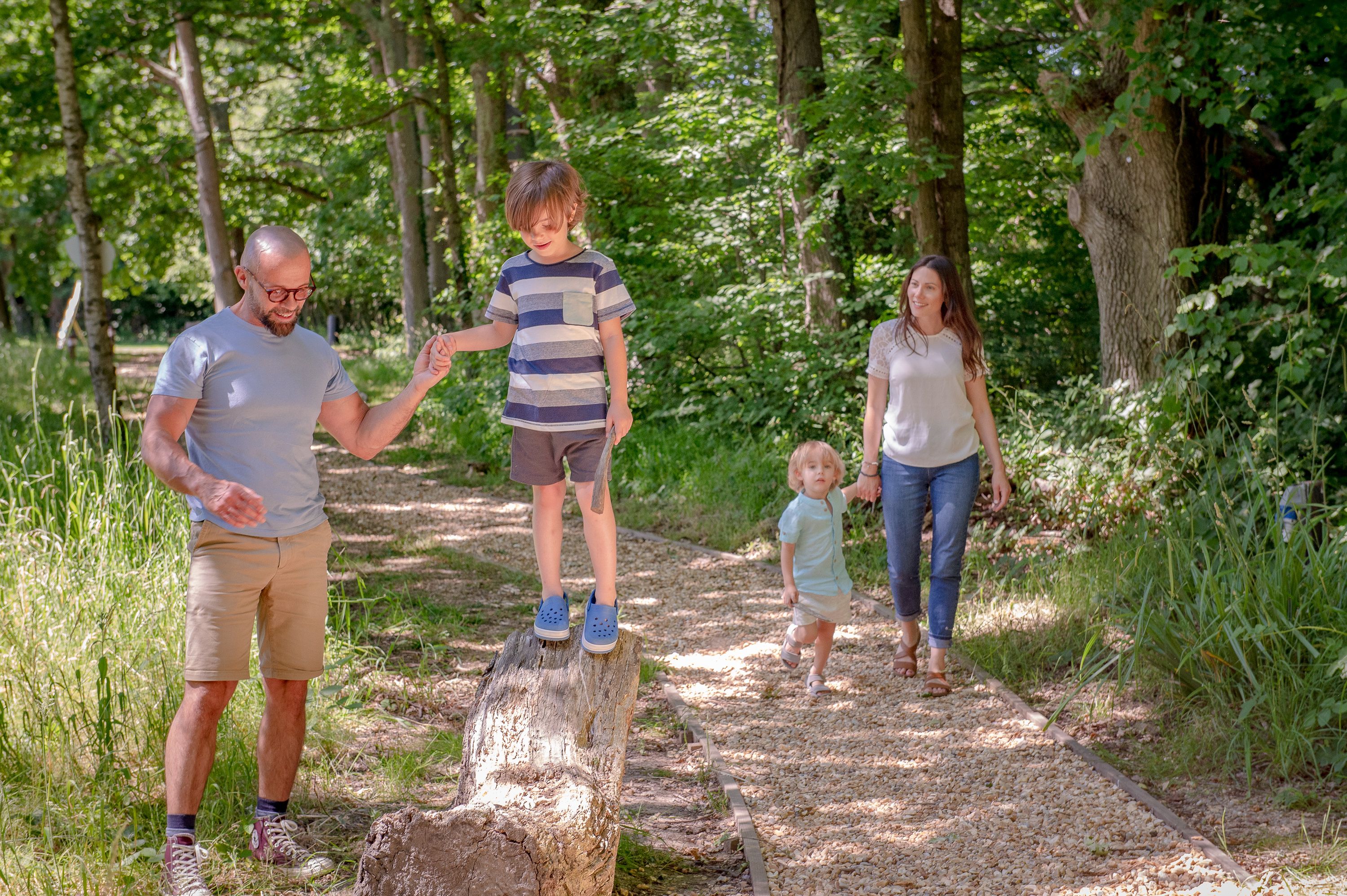 a family with two young children walking on a path through the forest