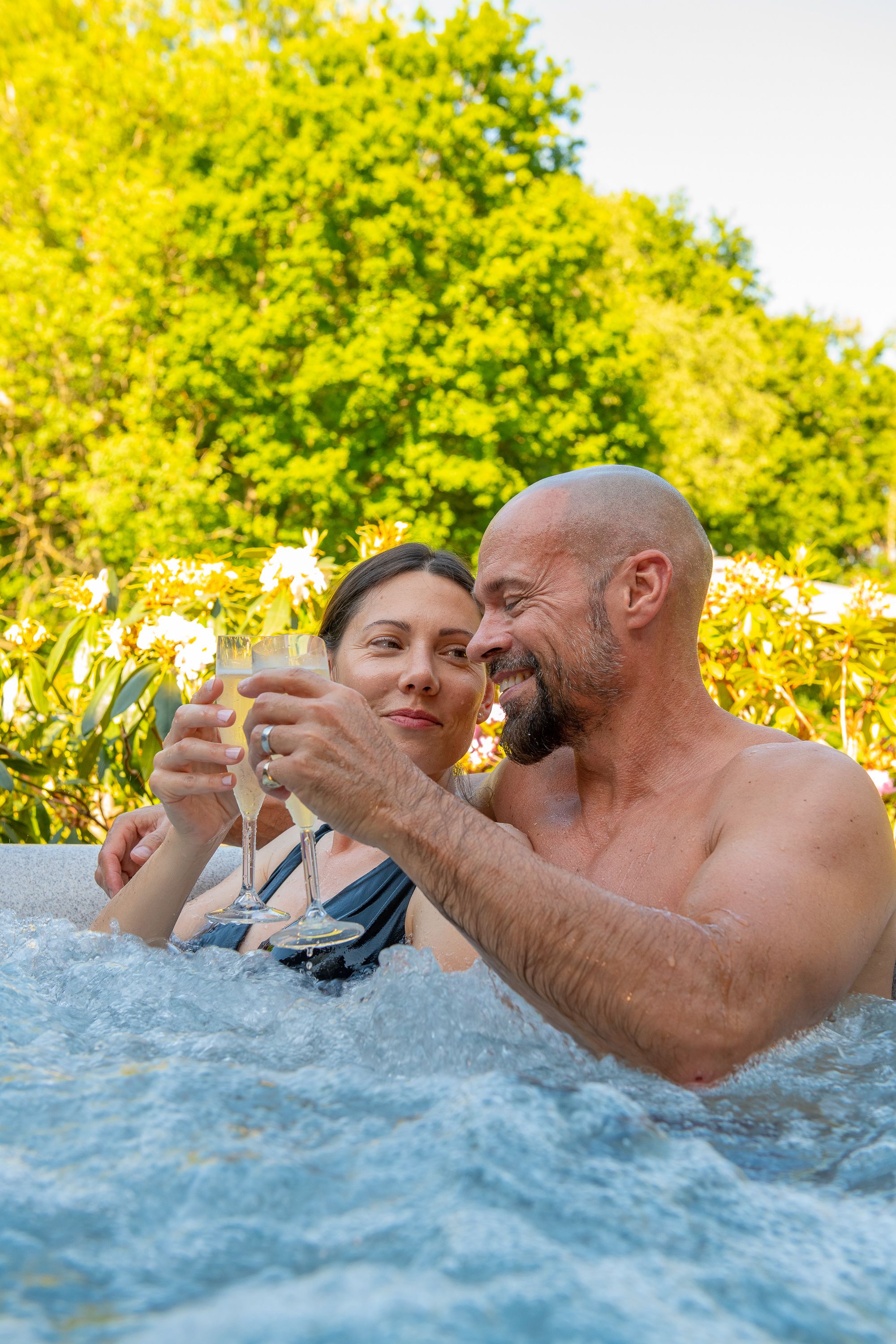 couple drinking champagne in a hot tub outdoors