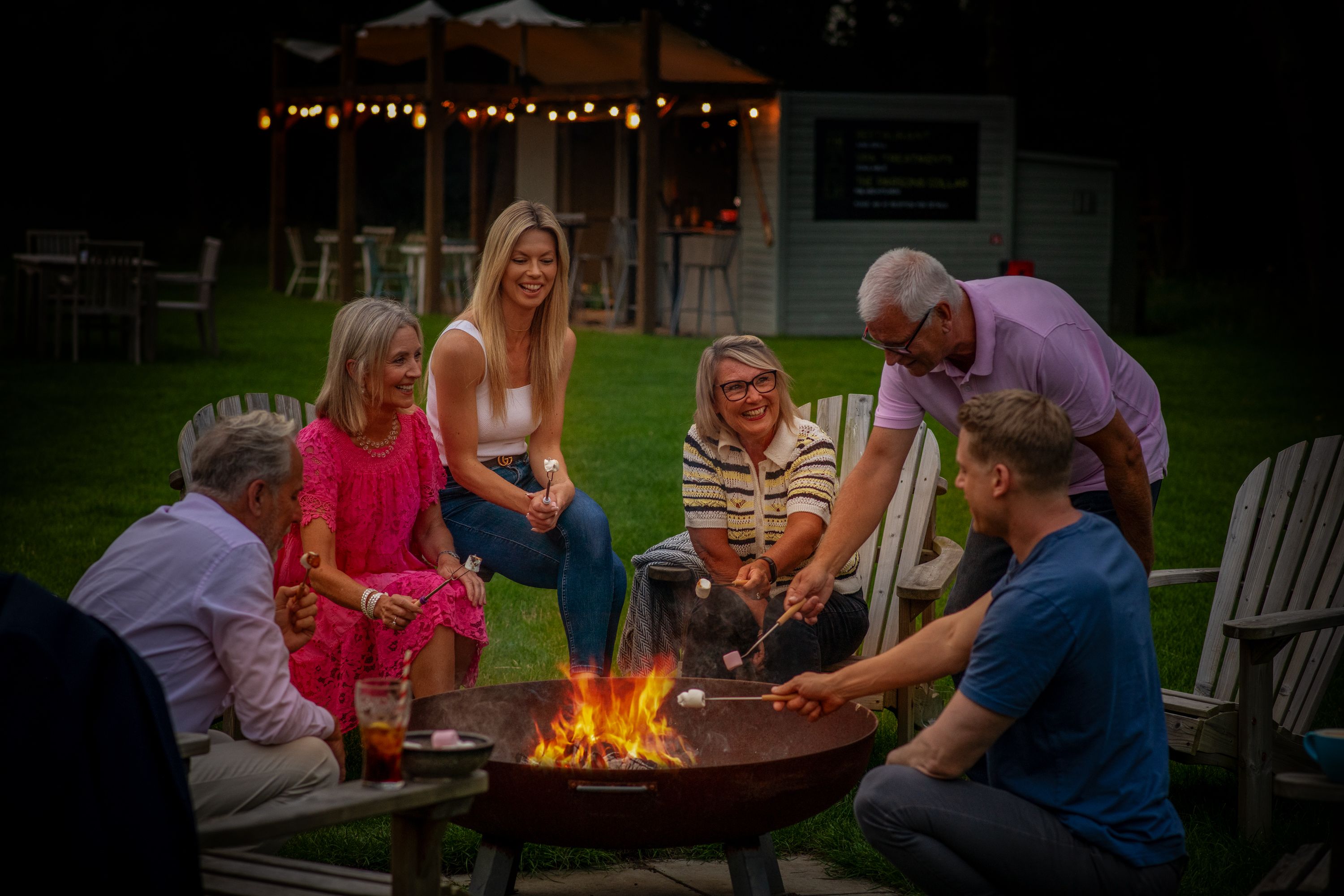 a group of people roasting marshmallows around a fire pit