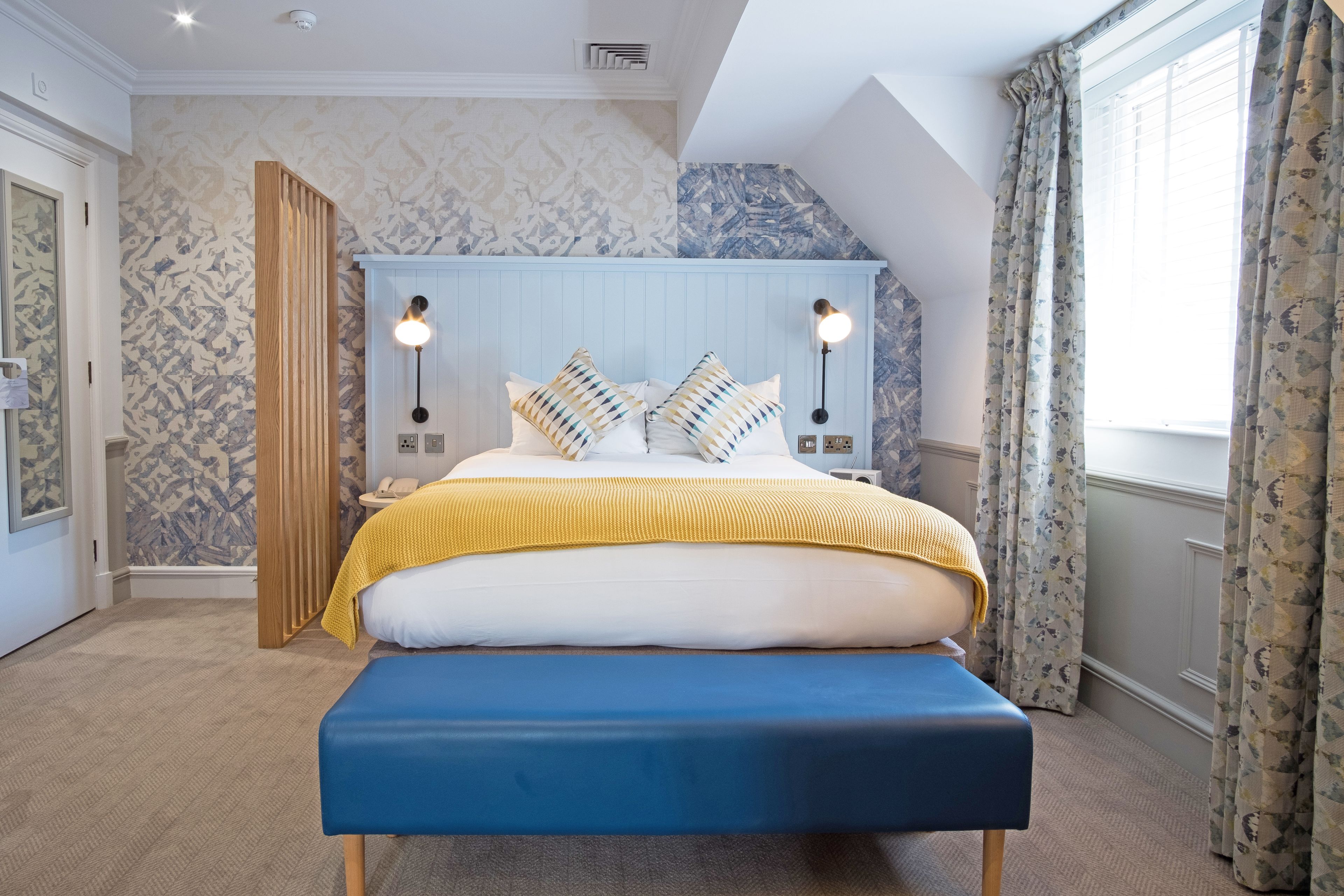 bright bedroom with king bed and blue bench