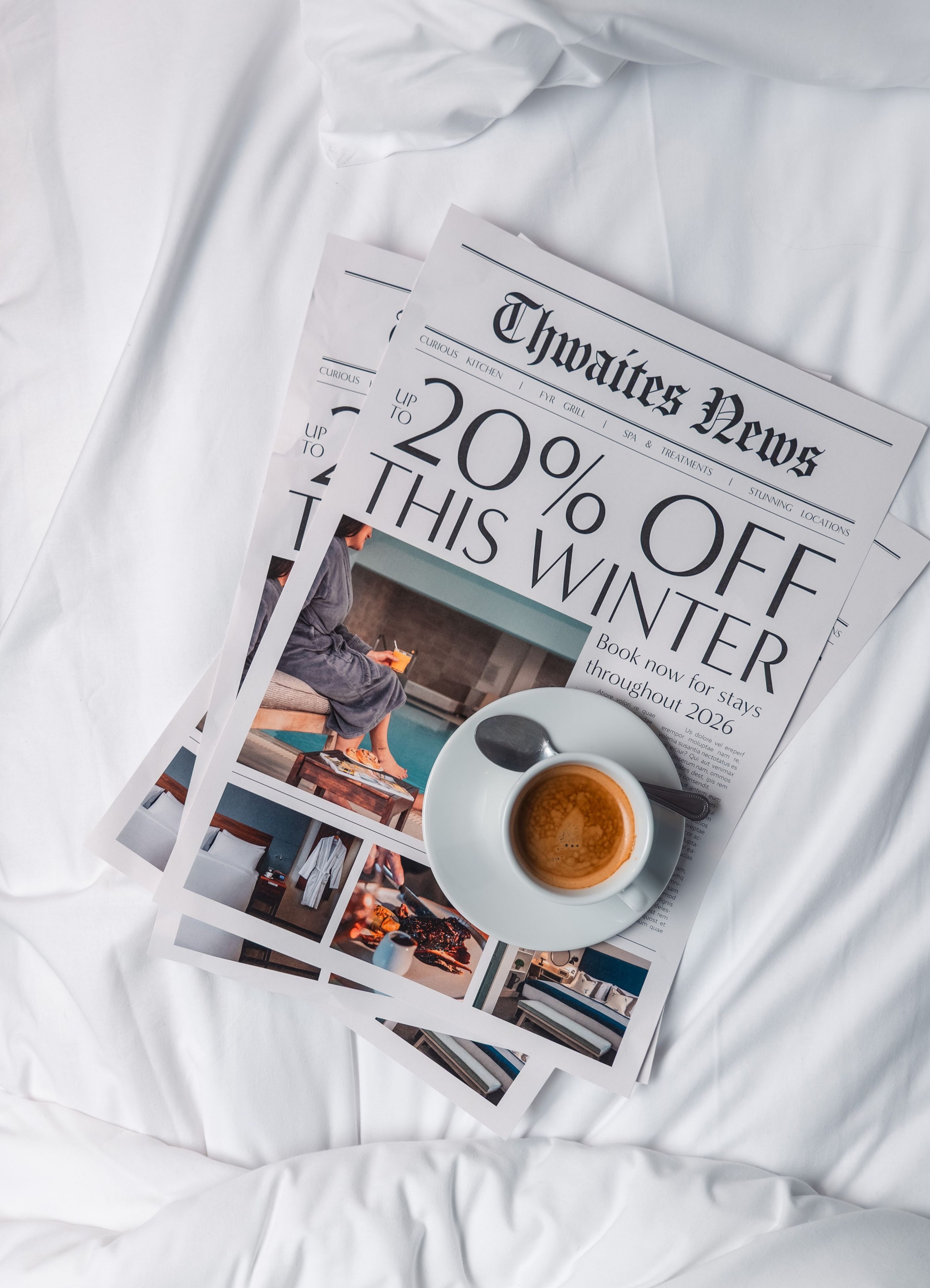 Newspaper and coffee on hotel bed with the headline "Up to 20% off winter sale"